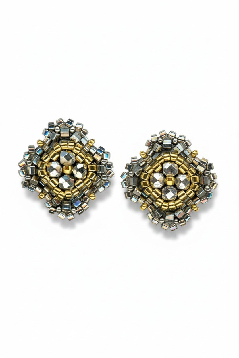 The MIGUEL ASES - PYRITE MIYUKI STUD EARRINGS by MIGUEL ASES, INC. feature square handcrafted studs with gold, silver, and pyrite beads in an intricate geometric pattern on a white background.
