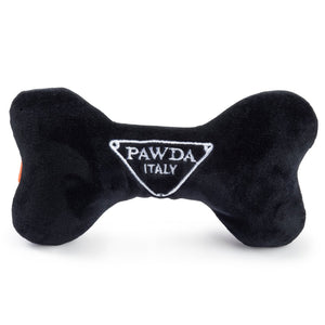 The HAUTE DIGGITY DOG PAWDA BONE DOG TOY is a chic black and orange plush bone with "PAWDA" embroidered in white on the orange stripe—an essential accessory for your stylish pup.