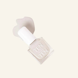 A glass bottle of TENOVERTEN - NAIL POLISH from the brand TEN OVER TEN, featuring a white cap and a dusty pink nail color. The front label displays "TEN OVER TEN" in white uppercase letters. This vegan, eight-free formula ensures both beauty and peace of mind. The background is plain and light-colored.