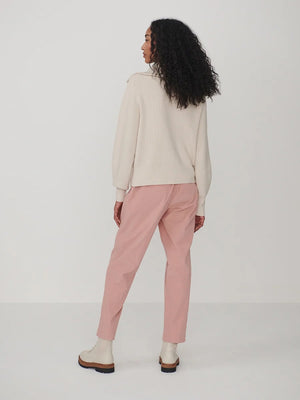 A person wearing a dark brown VARLEY - ENRICO ZIP-THROUGH KNIT JACKET featuring a ribbed soft viscose knit, a high collar, and a front zipper, ideal for cool weather layering.