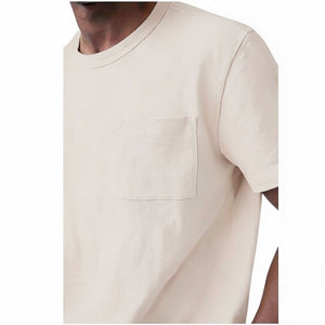 A man with short hair and a beard wears the MACK WELDON Heavyweight Slub Cotton Pocket T-Shirt in Froth, standing against a plain white background with his hands behind his back, looking at the camera.