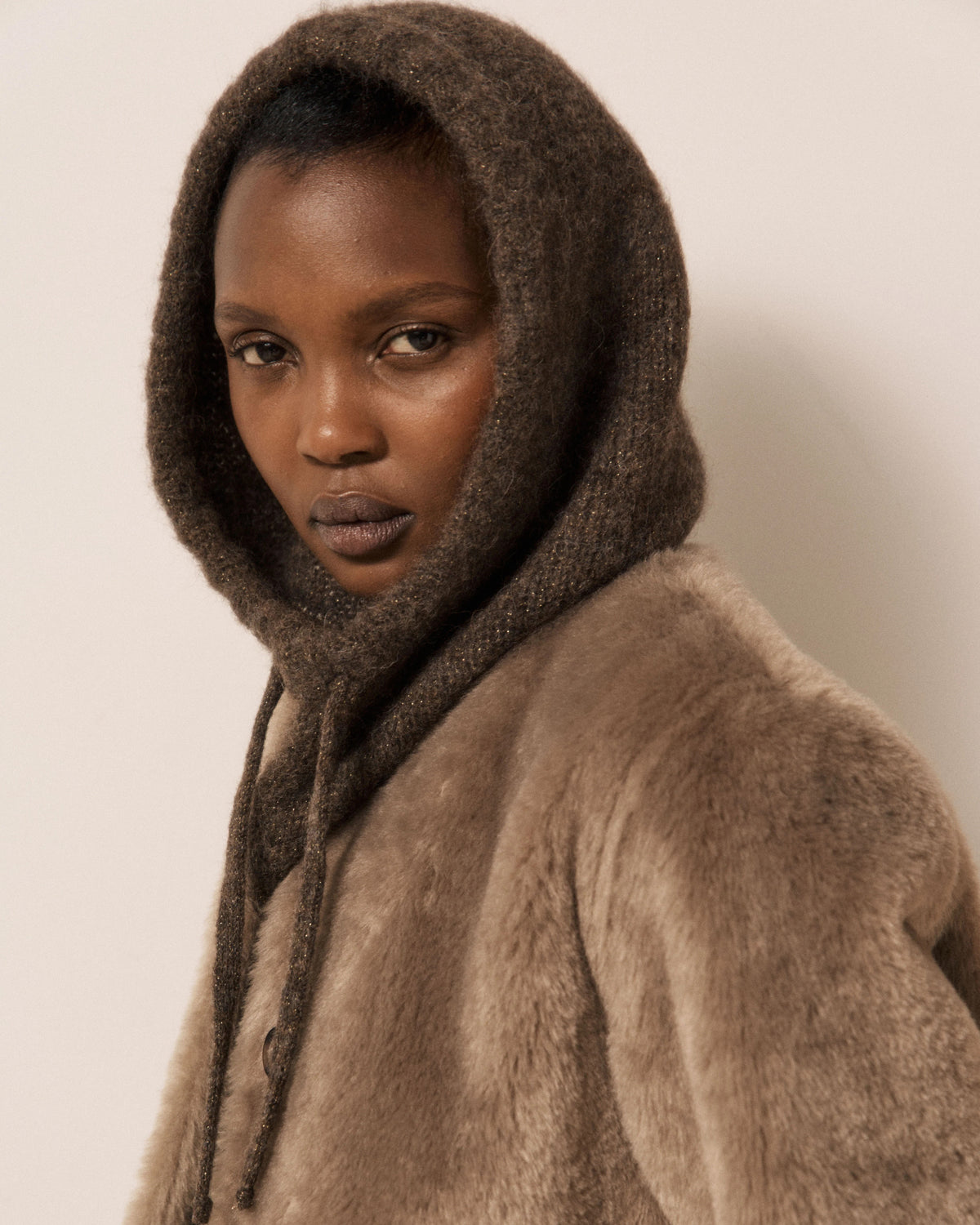Wearing the HARTFORD MEVA Hood in Chocolate, a person gazes seriously at the camera against a plain background.