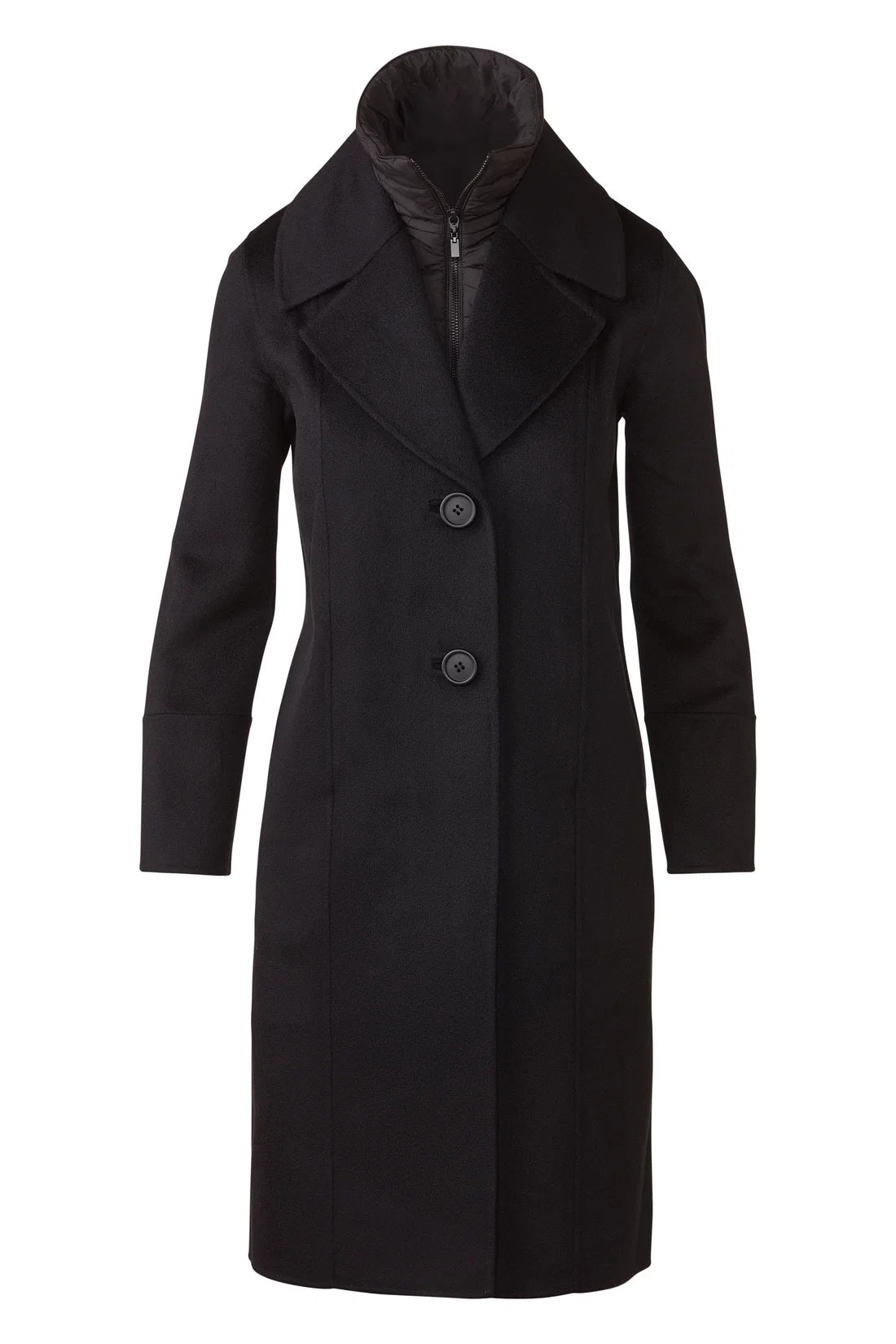 A woman stands indoors by a large window, smiling at the camera, wearing blue jeans and the KINROSS CASHMERE Quilted Insert Notch Collar Coat in black layered over a quilted black jacket.
