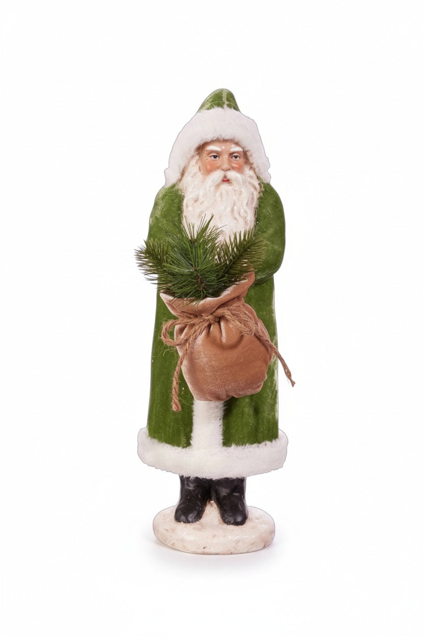 The RAZ IMPORTS OLD WORLD GREEN VELVET SANTA 17.25" features Santa in a green coat and hat with white trim, holding a burlap sack of evergreens, standing on a round eco-friendly paper pulp base.