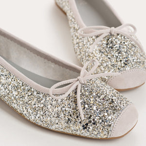 The REQINS HARMONY Sequin Ballerina Flat in Ice features a sparkling design with subtle pink trim and a small bow on the toe, shown from above against a plain light background.