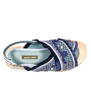 Introducing the MEHER KAKALIA DA GAMMA BLOC SANDAL in Yacht Blue Deep Blue: a chic sandal with blue cross-straps, intricate hand embroidery, frayed edges, and a decorative platform sole featuring blue and white braid accents. It includes an adjustable ankle strap with a gold buckle.