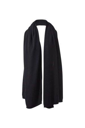 A person wearing a light gray top, black pants, and the KINROSS CASHMERE - FWT CRYSTAL WRAP by KINROSS with delicate dotted patterns stands against a plain white background.