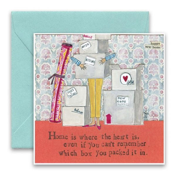 The CURLY GIRL DESIGNS - HOME IS WHERE CARD by CURLY GIRL DESIGN, INC. features an illustration of a person holding several labeled moving boxes, obscuring their face. Surrounding boxes are labeled with room names. The text reads, "Home is where the heart is, even if you can't remember which box you packed it in." The background showcases happy-patterned wallpaper celebrating the new home.