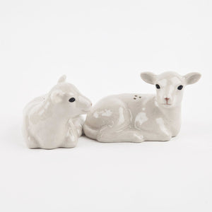 The QUAIL CERAMICS - LAMB SALT AND PEPPER SET by QUAIL DESIGNS features two hand-painted stoneware shakers shaped like lambs lying side by side, with a glossy finish and gentle expressions.
