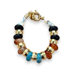 The HOLST & LEE - SEMI PRECIOUS BRACELET by HOLST & LEE is a chic accessory featuring alternating round, metallic gold and translucent brown beads. It has a unique clasp and a small, circular charm hanging from it. The evenly spaced and polished beads give it a stylish and elegant look.