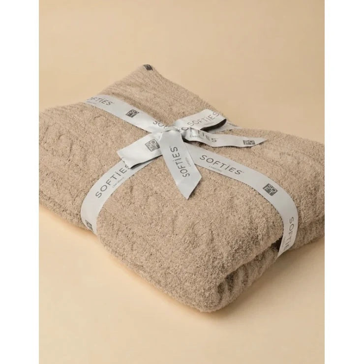 Folded off-white SOFTIES - CABLE KNIT MARSHMALLOW BLANKET tied with a branded ribbon.