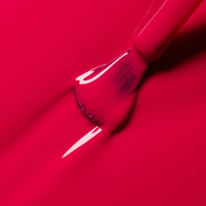 A bottle of MANUCURIST INC’s GREEN™ Nail Polish in the shade Peony, featuring a black cap and pink color visible through the clear glass.