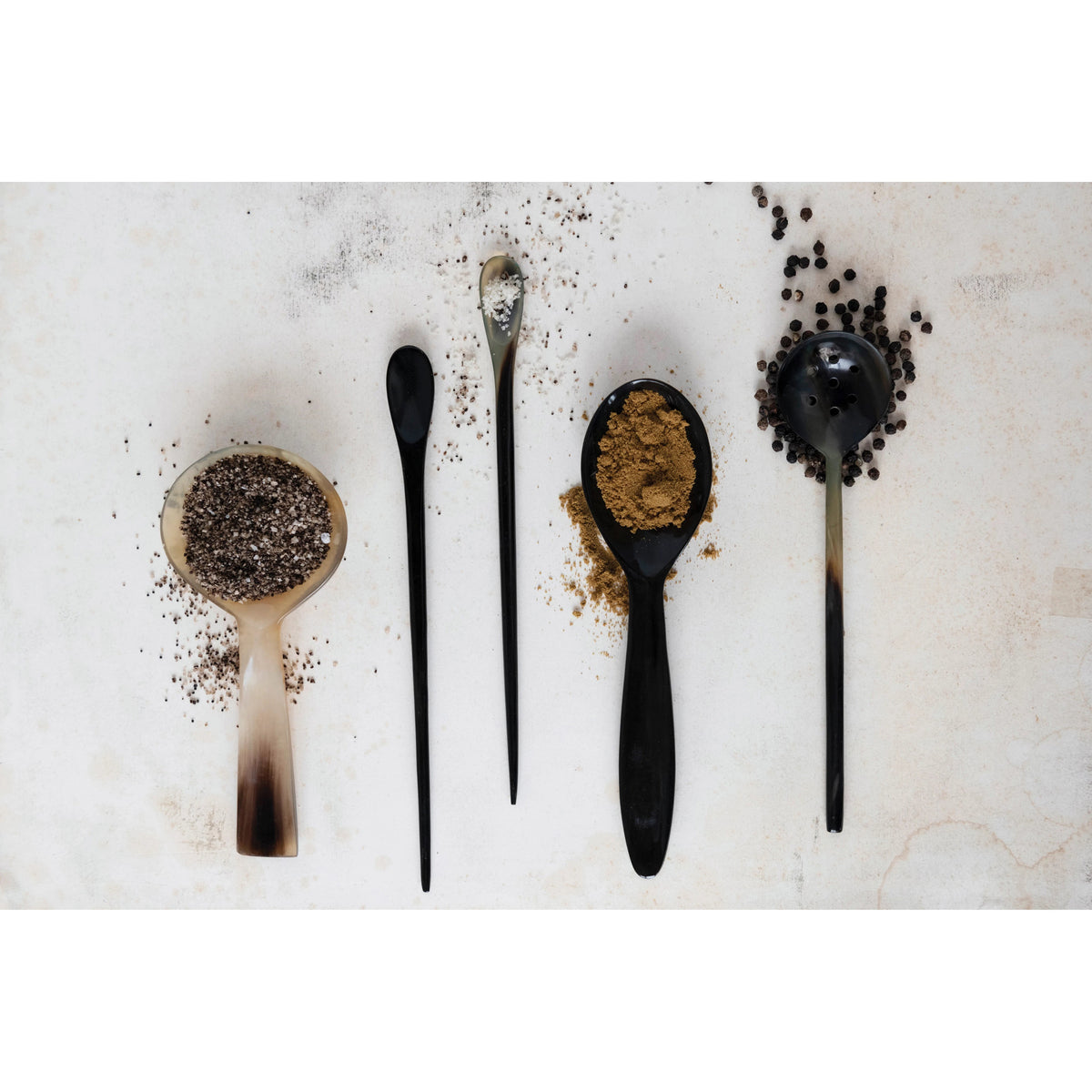 The HORN SPOON by CREATIVE COOP is a round, shallow spoon made from natural horn, featuring a light, translucent gradient from pale cream to dark brown at the handle&#39;s tip—ideal for stylish serving.