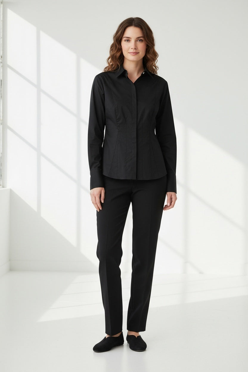 A woman with straight brown hair, wearing the HINSON WU - FRANCIS FITTED SHIRT—a tailored black button-up crafted from stretch polished cotton by HINSON WU—and black pants, stands with one hand in her pocket, gazing off to the side against a plain white background.