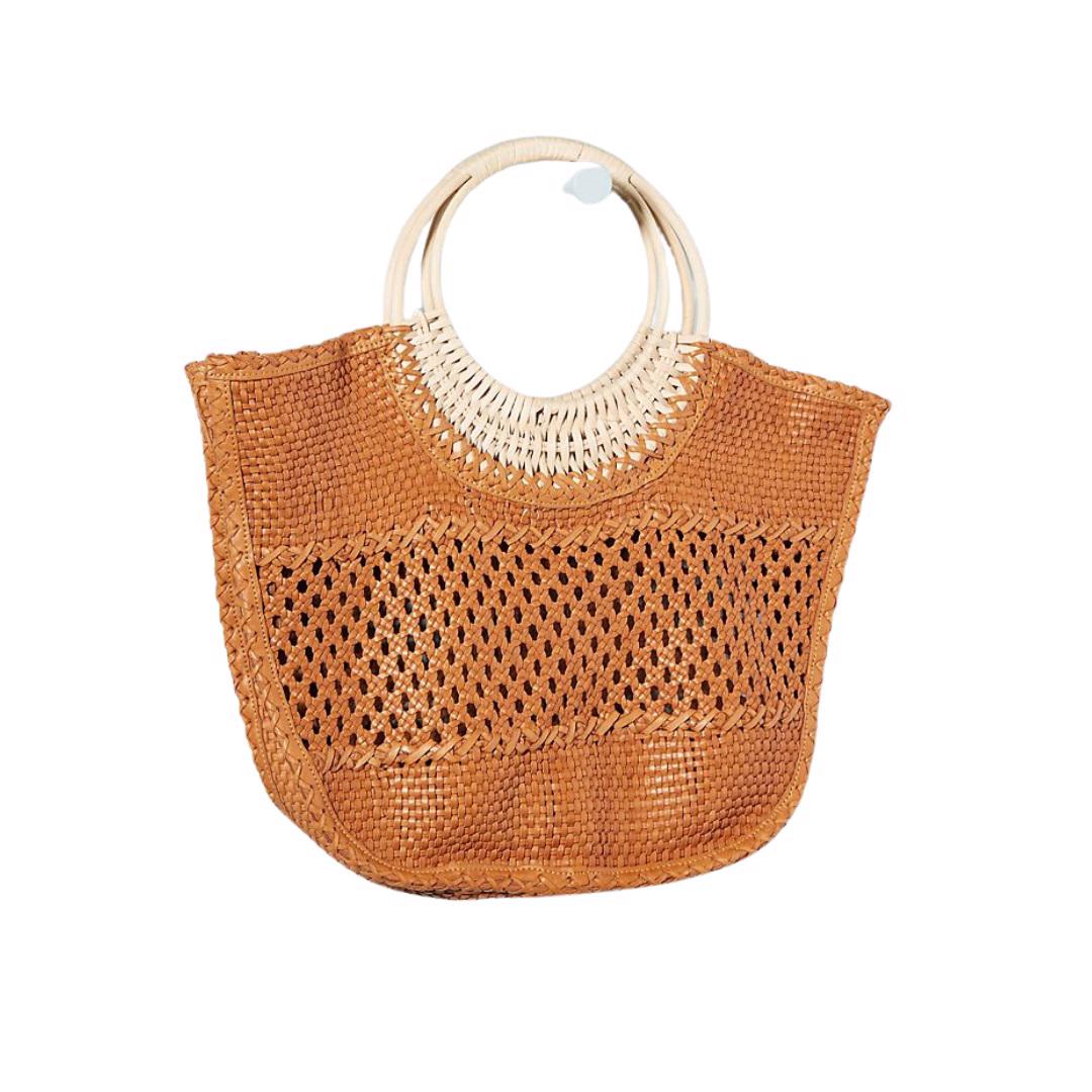 The WOVEN SUMMER BAG by EN SHALLA is a woven straw handbag with intricate detailing, perfect for groceries and market finds. The top half features tightly woven straw, while the lower half has a more open, lattice pattern. The handle consists of circular white rings, and the bag has a natural, earthy color.