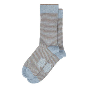A pair of AMANDA CHRISTENSEN TRUE STRIPE MID-CALF SOCKS IN SKY BLUE MELANGE, featuring gray and brown stripes with light blue toes, heels, and cuffs. These Italian-made socks have printed text on the sole.