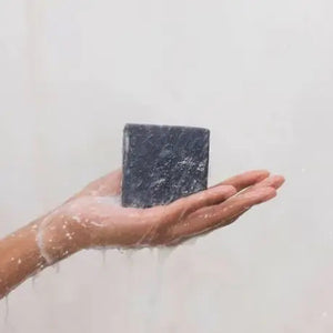 The KITSCH - CHARCOAL DETOXIFYING BODY WASH BAR, a black square solid soap on a matching box, is gentle, vegan, and all-natural. Detoxify pores and refresh your skin with this 4 oz. (113g) zero-waste treat while embracing an eco-friendly lifestyle.