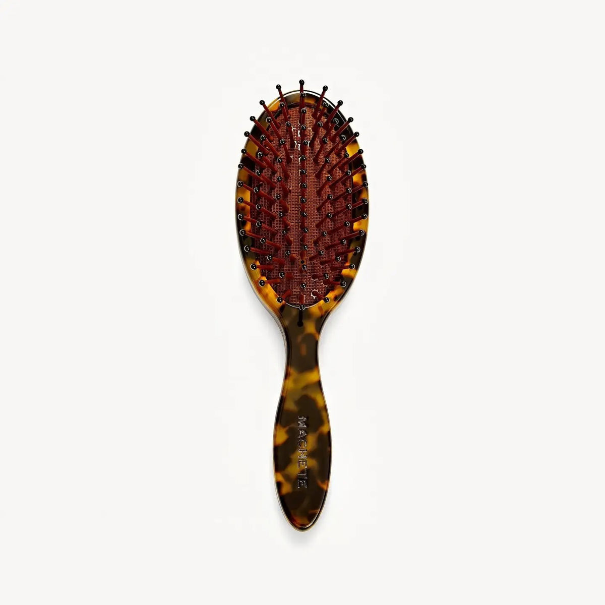 A close-up of the MACHETE Petite Travel Detangling Hair Brush in Tortoise, crafted from Italian acetate with a cushioned base and rounded bristle tips, set against a plain white background.