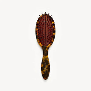 A close-up of the MACHETE Petite Travel Detangling Hair Brush in Tortoise, crafted from Italian acetate with a cushioned base and rounded bristle tips, set against a plain white background.
