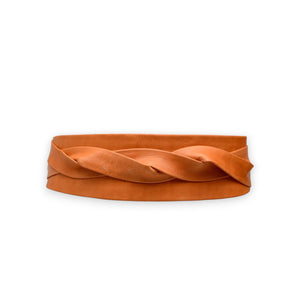 The ADA WRAP BELT IN PAPAYA, an orange leather belt with a twisted design, is handmade by artisans using genuine Argentinian vegetable-tanned leather and showcased on a plain white background.