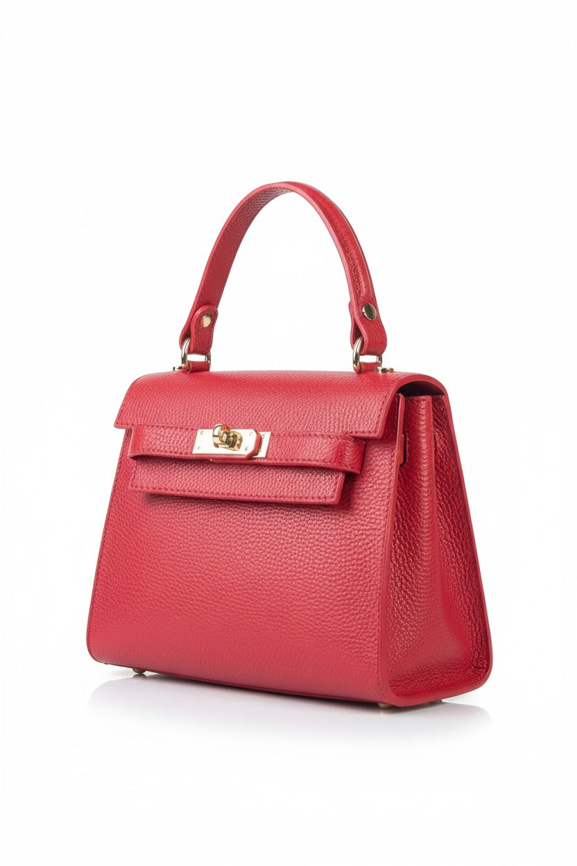 The LE BORSETTE LEATHER SATCHEL BAG is a small, structured satchel-shaped handbag in light pink, featuring a gold clasp at the front. It boasts a single top handle, an adjustable shoulder strap, and two gold-tone hardware pieces on either side of the handle. The textured leather adds to its luxurious and elegant appearance against the plain white background.