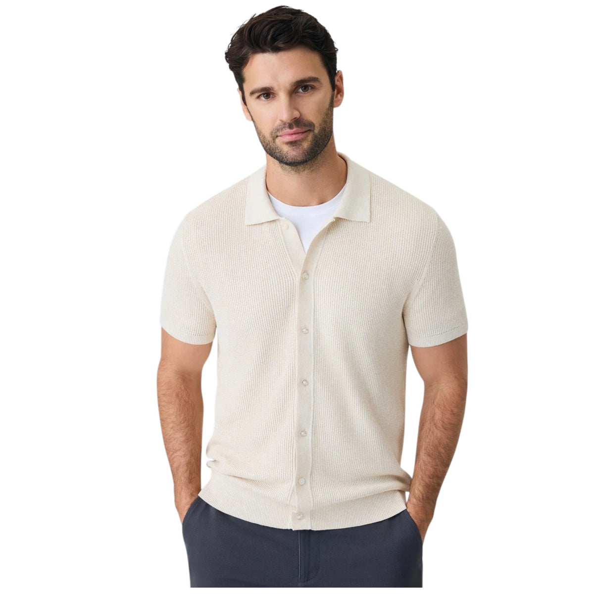 A close-up of a person wearing the MACK WELDON Tech Linen Button Up Sweater Polo in Latte Heather with dark pants, their arm relaxed by their side against a neutral background.