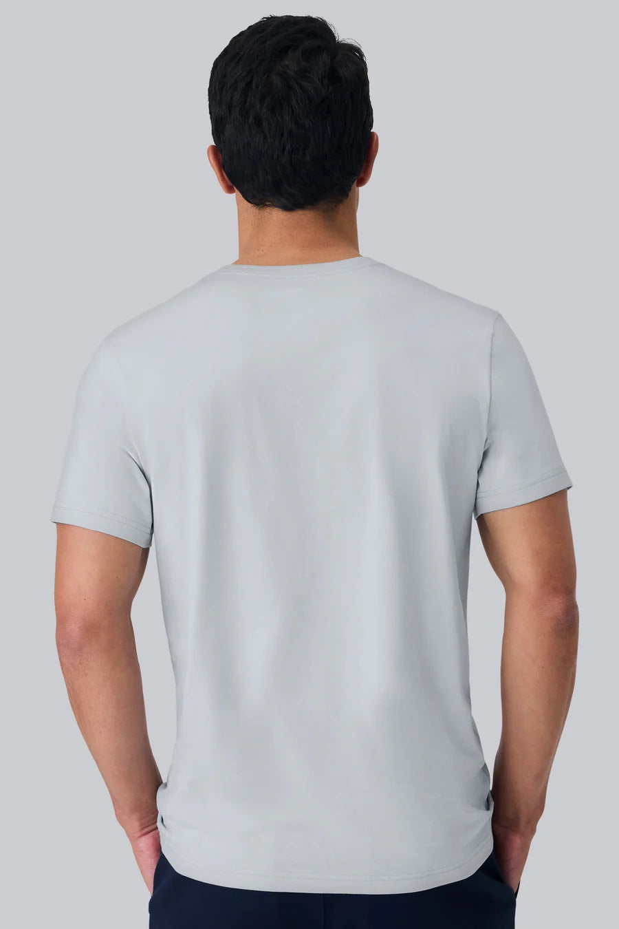 A man with short dark hair wears the MACK WELDON Pima Crew Neck T-Shirt in Steam and dark pants, standing against a plain light gray background and looking at the camera with a neutral expression.