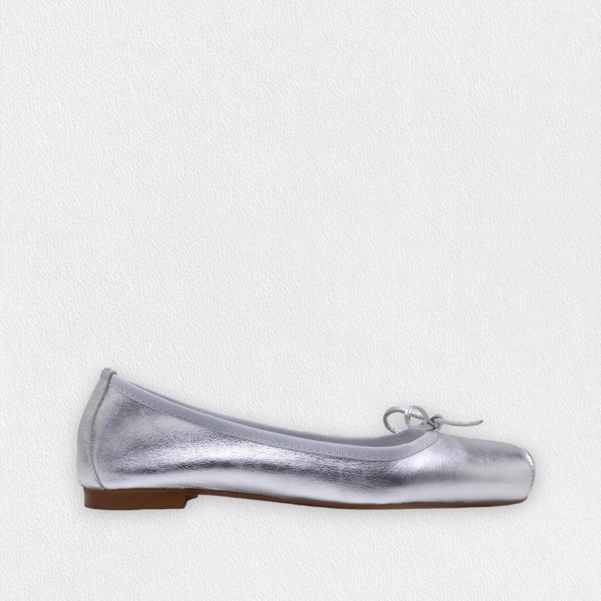 The MICHELE LOPRIORE - PALOMA ballet flat with a square toe, crafted from genuine silver leather, features a delicate bow on the front and a low-profile brown sole. Made in Italy, this elegant shoe is set against a plain white textured background.
