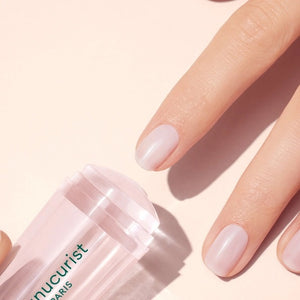 A hand with a light pink French manicure rests beside the MANUCURIST - MANI STAMPER by MANUCURIST INC on a pale background.