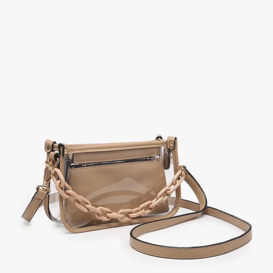 Introducing the CLEAR CROSSBODY BAG by JEN &amp; CO: A stylish handbag crafted from vegan leather, showcasing a layered beige design with an open top and a visible zipper pocket. This bag is elegantly framed by a transparent outer layer and is complemented by a chunky beige chain strap for additional style and versatility.