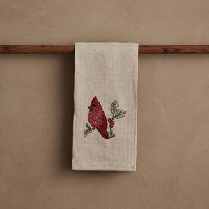 A RED CARDINAL LINEN TEA TOWEL by CORAL & TUSK made of beige natural flax fiber, embroidered with a red cardinal perched on a branch with berries and green leaves.