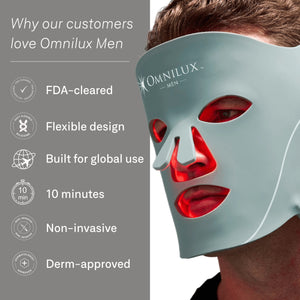 A man intently examines the OMNILUX - MENS MASK, a glowing red LED mask designed for skin rejuvenation with advanced red light therapy, featuring eye, nose, and mouth cutouts.