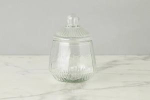 ETUHOME Bistro Glass Biscuit Jars with lids sit on a wooden tray, filled with snacks and orange-wrapped candies. The classic jar design by ETUHOME stands out against the softly blurred background.