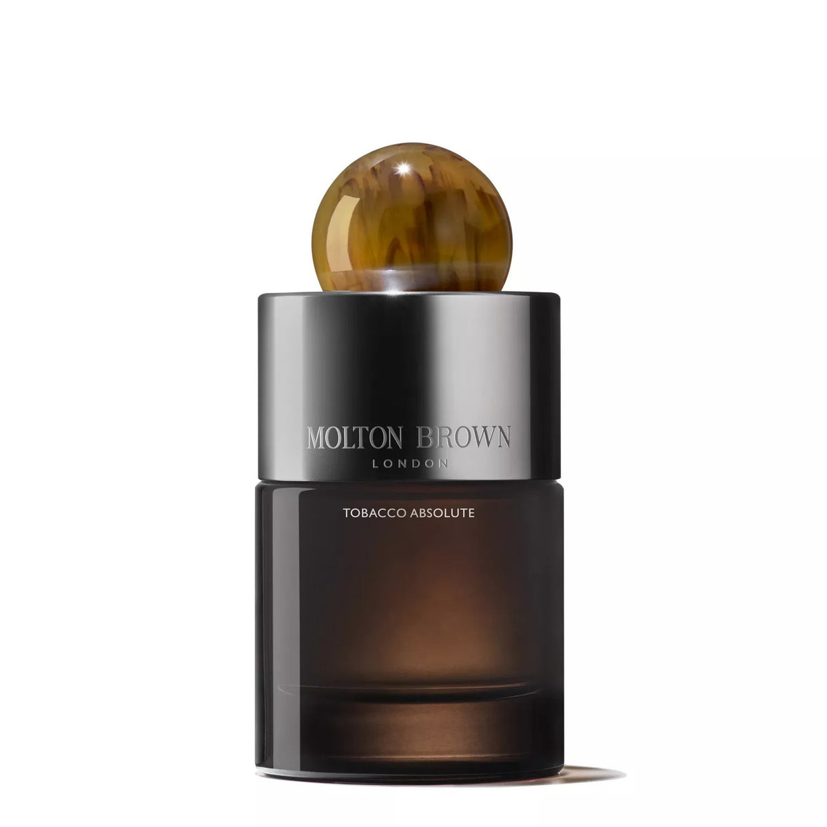 A 100ml bottle of MOLTON BROWN - TOBACCO ABSOLUTE EAU DE PARFUM, featuring a dark glass body, metallic cap, and round amber top, is displayed against a white background to reflect the woody fragrance's essence.