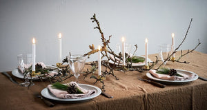 Four UYUNI - WHITE MINI TAPER CANDLES WITH CLIPS 0.5X5.4 by PIFFANY, each with a glowing flame, are displayed upright in gold holders that feature clamp bases, all set against a plain white background.