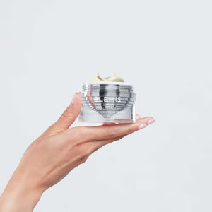An ELEMIS - ULTRA SMART PRO-COLLAGEN DAY CREAM jar, an advanced moisturizer by ELEMIS - STEINER with adaptogenic technology, sits beside its silver box. The jar features a sleek lid, and the luxurious cream peeks out from the top.