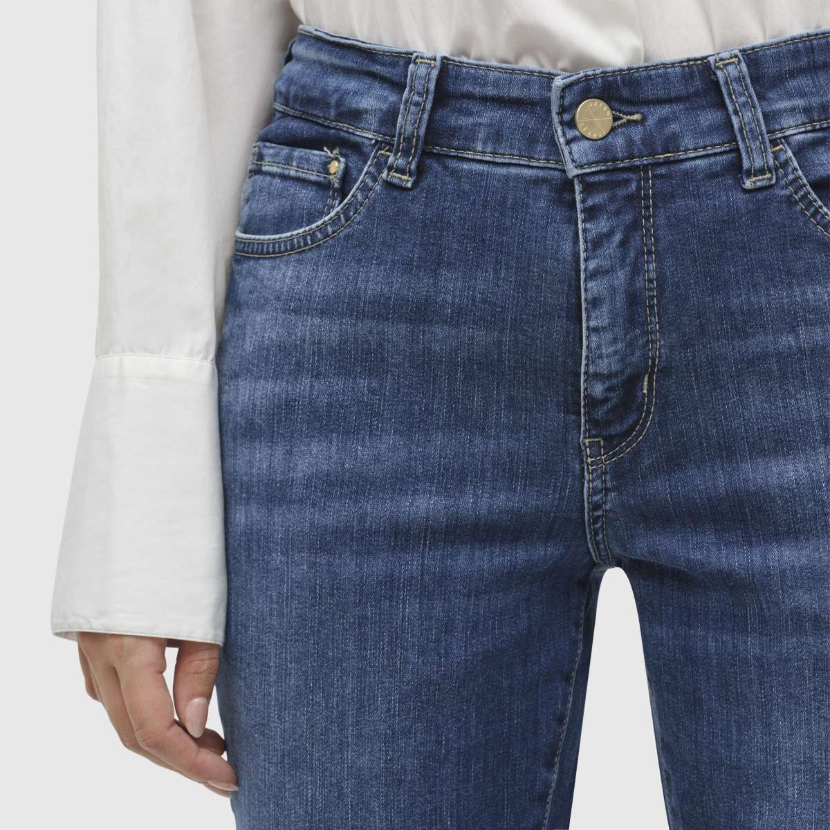 A person is standing against a plain white background, wearing MAC JEANS - DREAM KICK OUTWORN BLUE and white sneakers. The jeans are slightly flared at the bottom and feature typical denim stitching. The upper body of the person is not fully visible, but they appear to be wearing a white top.