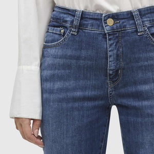 A person is standing against a plain white background, wearing MAC JEANS - DREAM KICK OUTWORN BLUE and white sneakers. The jeans are slightly flared at the bottom and feature typical denim stitching. The upper body of the person is not fully visible, but they appear to be wearing a white top.