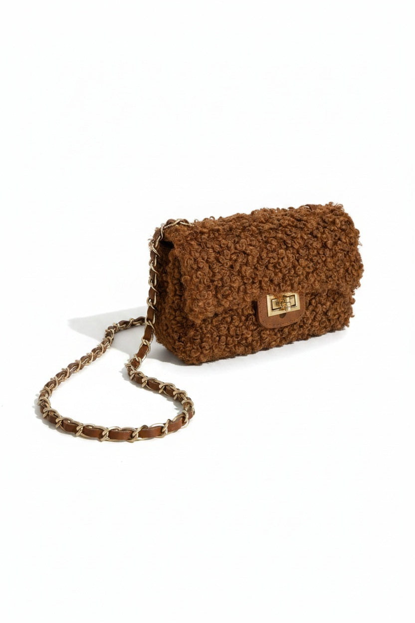 The VICARIO CINQUE Brescia Bag in brown by VICARIO CINQUE showcases a soft, curly bouclé texture with a modern rectangular gold clasp on the front, embodying Italian-inspired chic style and contemporary elegance.
