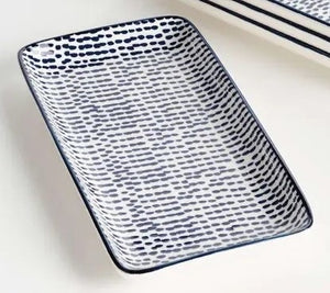 The NAPA HOME AND GARDEN Blue and White Speckled Stria Tray features a rectangular ceramic design with a white base, navy speckles, and a slim navy rim—ideal for bringing modern elegance to your table.