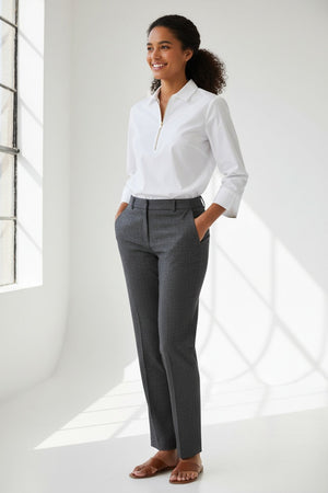 A woman stands against a plain, light background wearing the HINSON WU Alessa 3/4 Sleeve Shirt in stretch polished cotton—a crisp white blouse with a collared neckline and partial front zipper—paired with dark pants.