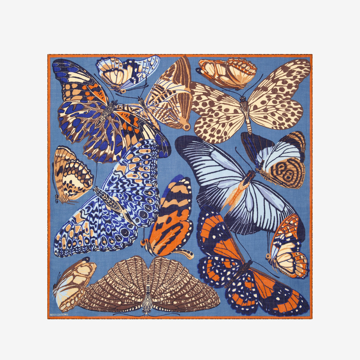 A woman wears the INOUI EDITIONS PAPILLON (BUTTERFLIES) wool square scarf in duck blue, featuring abstract nature-inspired designs, paired with a beige sweater. Only her lower face and neck are visible.