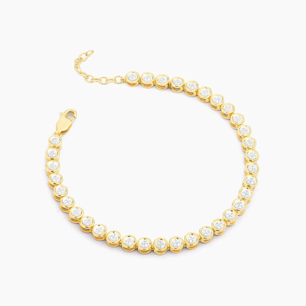 The ELLA STEIN - DIAMOND ESSENTIAL TENNIS BRACELET by ELLA STEIN features round, clear natural diamonds set in individual gold bezels, arranged in a single row with an adjustable chain and lobster clasp, displayed on a white background.