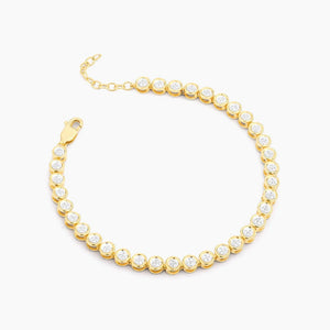 The ELLA STEIN - DIAMOND ESSENTIAL TENNIS BRACELET by ELLA STEIN features round, clear natural diamonds set in individual gold bezels, arranged in a single row with an adjustable chain and lobster clasp, displayed on a white background.