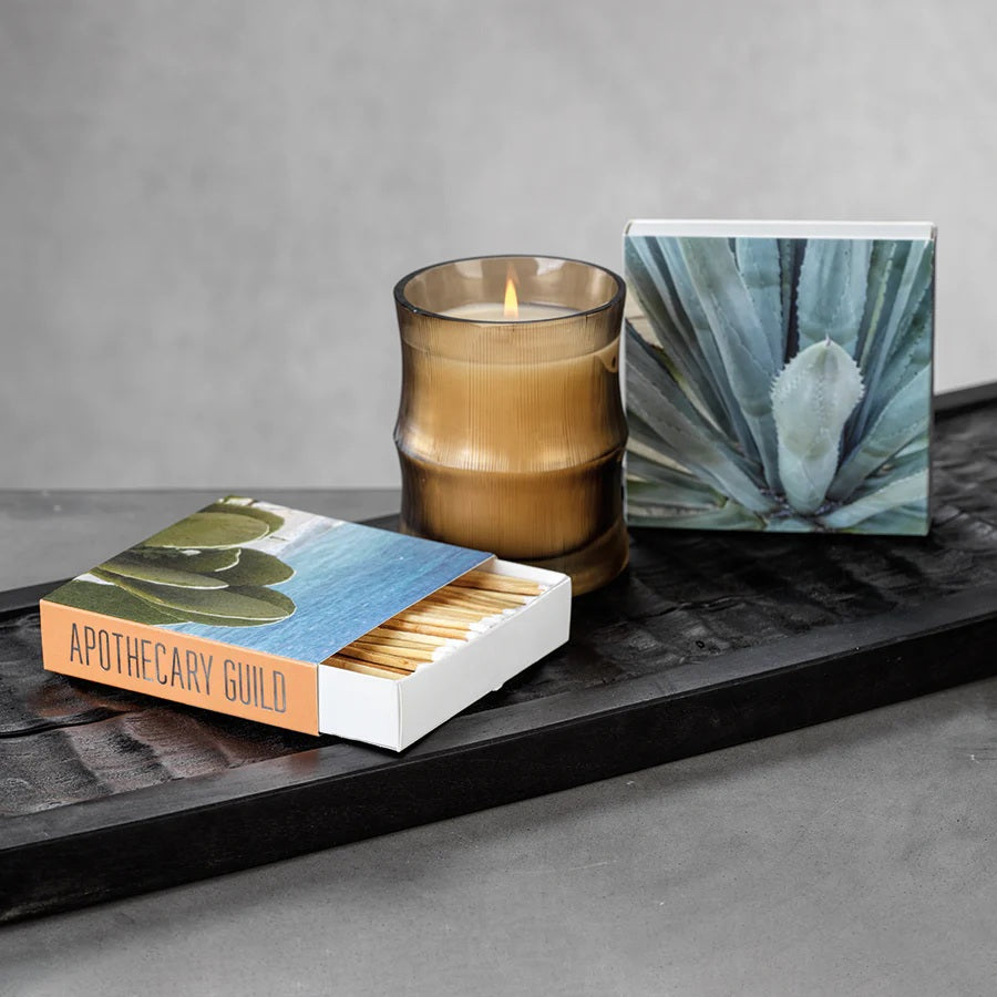 The MATCH BOX - AGAVE by ZODAX features two square designs—one closed and one open to reveal long, decorative matchsticks—with "ZODAX" branding on both the front and side.
