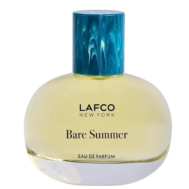 The LAFCO - FINE FRAGRANCE, BARE SUMMER 50ML perfume bottle, featuring a blue cap and displayed alongside delicate grasses, showcases its fresh and uplifting scent inspired by the sea and sand dunes. The text highlights opening, heart, and base fragrance notes that evoke the essence of summer. This vegan scent from LAFCO offers a clean, natural allure perfect for warm days.