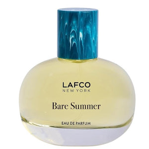 The LAFCO - FINE FRAGRANCE, BARE SUMMER 50ML perfume bottle, featuring a blue cap and displayed alongside delicate grasses, showcases its fresh and uplifting scent inspired by the sea and sand dunes. The text highlights opening, heart, and base fragrance notes that evoke the essence of summer. This vegan scent from LAFCO offers a clean, natural allure perfect for warm days.