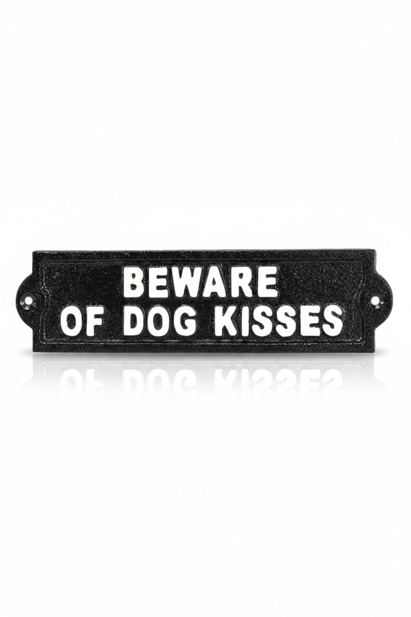 A rectangular black BEWARE OF DOG KISSES SIGN features white embossed text reading “BEWARE OF DOG KISSES.”.
