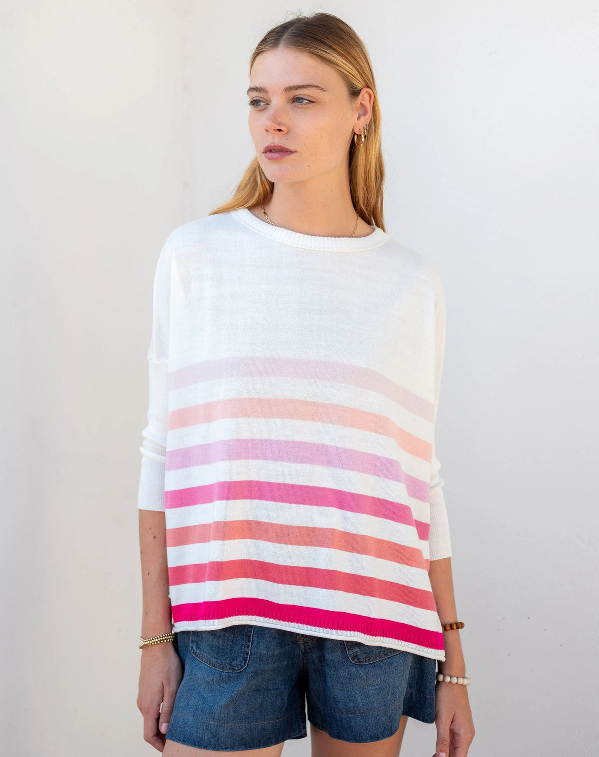 Woman wearing the MERSEA - CATALINA CREWNECK SWEATER, white with two black stripes, paired with denim shorts and a gold necklace—an essential piece from MERSEA for effortless, versatile style.