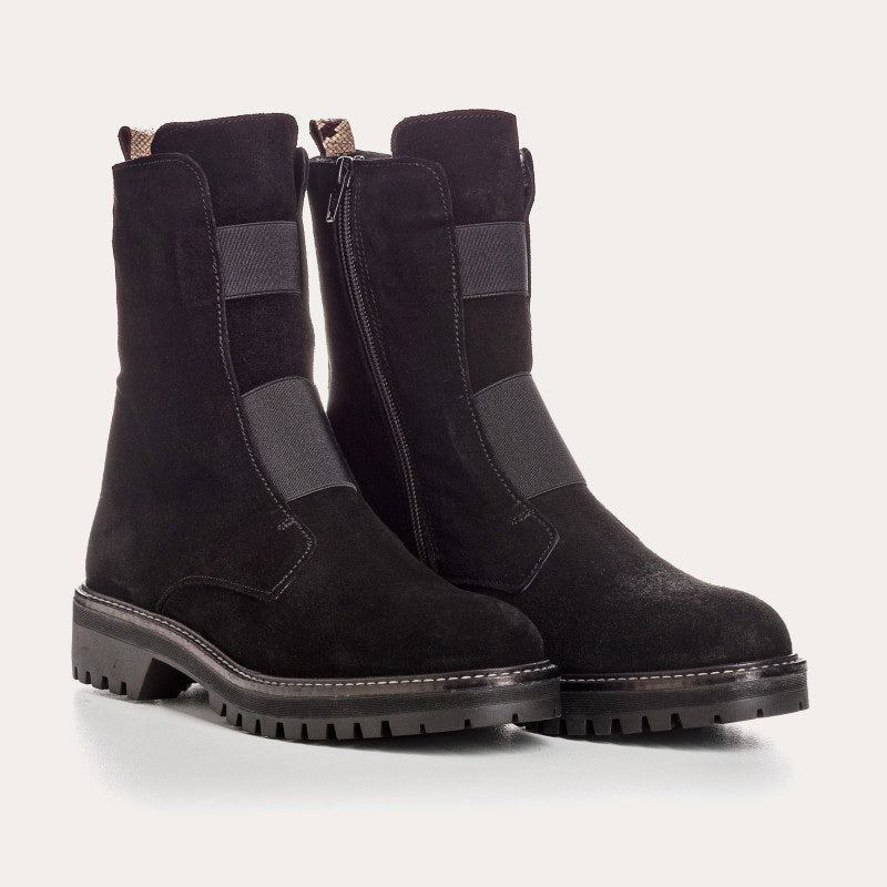 The REQINS - DUSKY SUEDE ANKLE BOOT IN NOIR features black suede leather, chunky cleated rubber soles, elastic panels on the front, and side zippers, and is displayed on a light background.